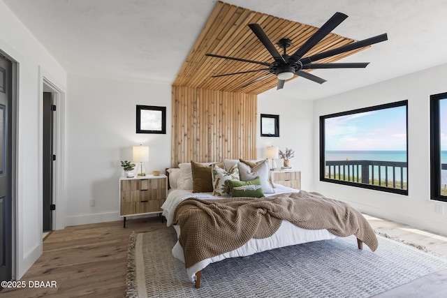 bedroom featuring a water view, ceiling fan, and dark wood-type flooring