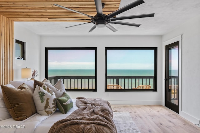 bedroom featuring a water view, ceiling fan, multiple windows, and light wood-type flooring