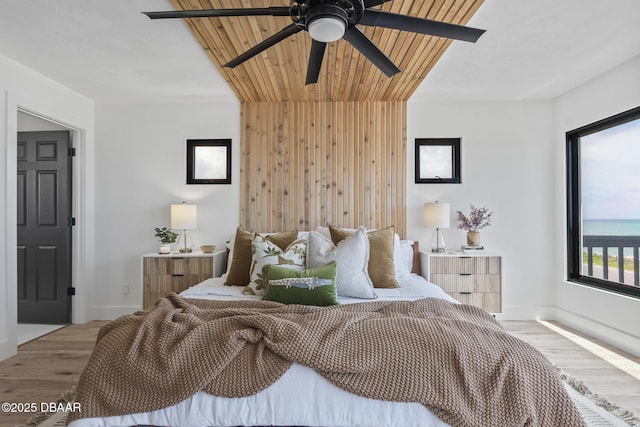 bedroom with wood-type flooring, ceiling fan, and wood walls