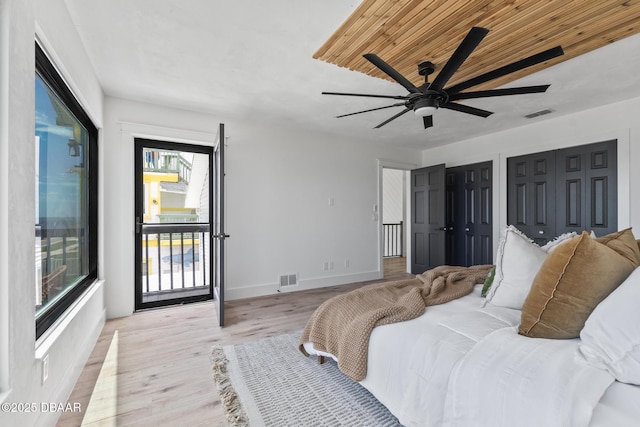 bedroom with wooden ceiling, multiple closets, light wood-type flooring, ceiling fan, and access to exterior