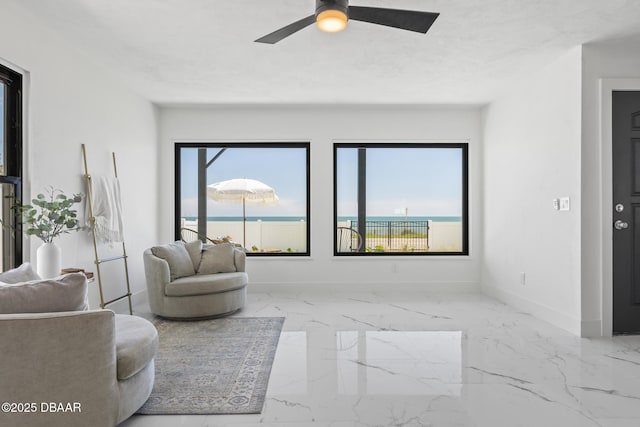 living room with a wealth of natural light, ceiling fan, and a water view