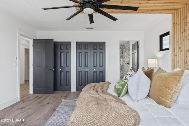 bedroom with ceiling fan, two closets, and light wood-type flooring