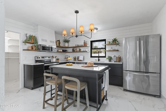 kitchen with a kitchen island, a breakfast bar, pendant lighting, a chandelier, and stainless steel appliances