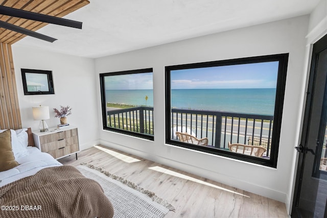 bedroom featuring hardwood / wood-style floors, a beach view, and a water view