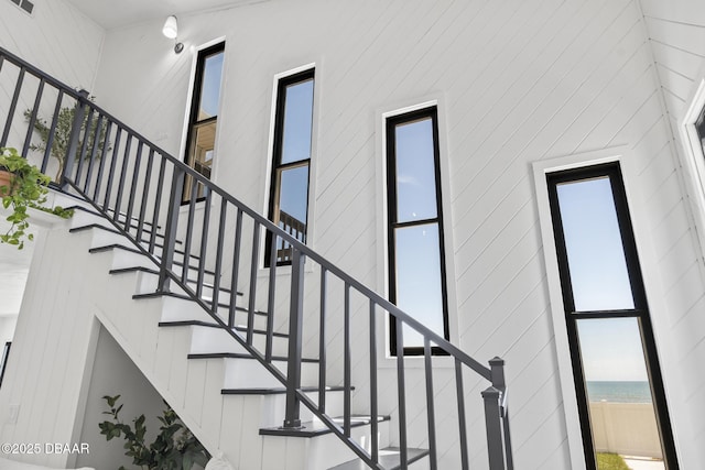 staircase featuring a towering ceiling and a water view