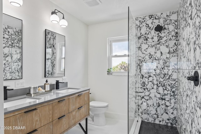 bathroom featuring vanity, a tile shower, and toilet