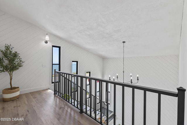 corridor featuring lofted ceiling, hardwood / wood-style floors, and a notable chandelier