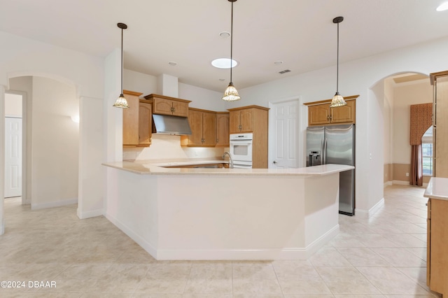 kitchen featuring kitchen peninsula, light tile patterned floors, decorative light fixtures, and stainless steel fridge with ice dispenser