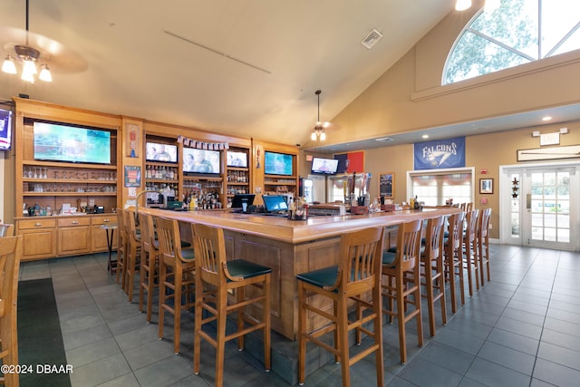 bar with a healthy amount of sunlight, high vaulted ceiling, tile patterned flooring, and ceiling fan