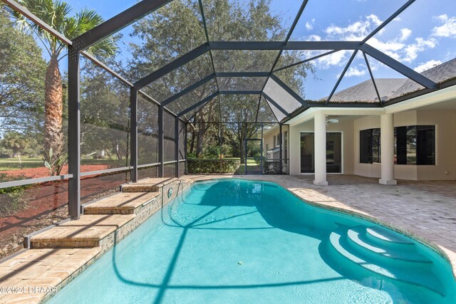 view of pool with a patio, ceiling fan, and glass enclosure