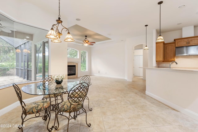 dining space featuring sink, light tile patterned floors, and ceiling fan with notable chandelier