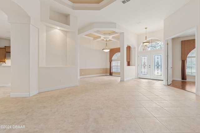 entrance foyer featuring coffered ceiling, french doors, light tile patterned floors, and decorative columns