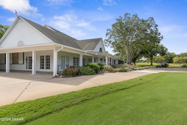 view of side of home featuring covered porch and a yard