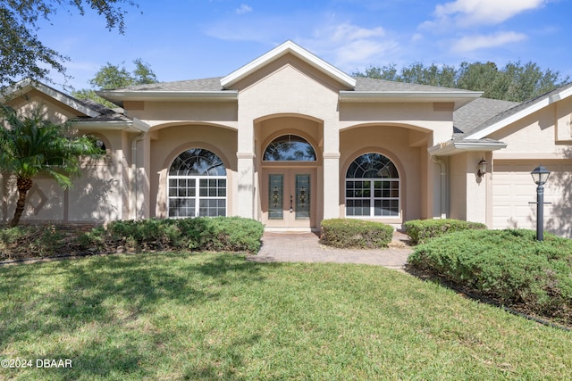 exterior space with a garage, a lawn, and french doors