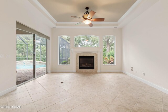 unfurnished living room featuring a tray ceiling, ceiling fan, and plenty of natural light