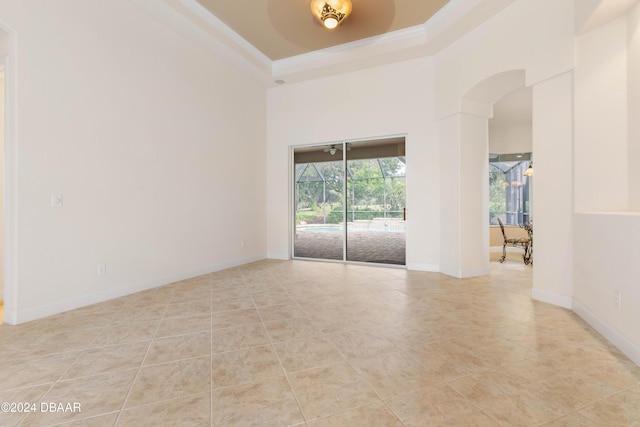 tiled spare room with a high ceiling, ornamental molding, and a raised ceiling