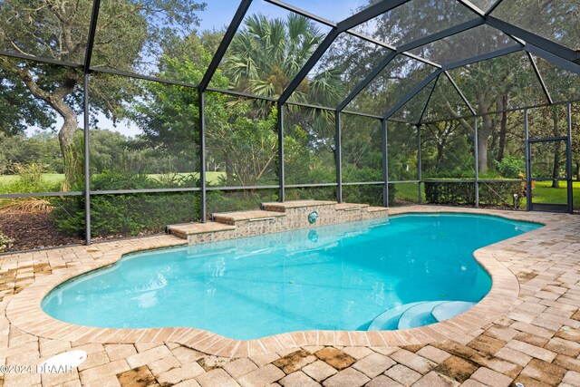 view of swimming pool featuring a patio and a lanai