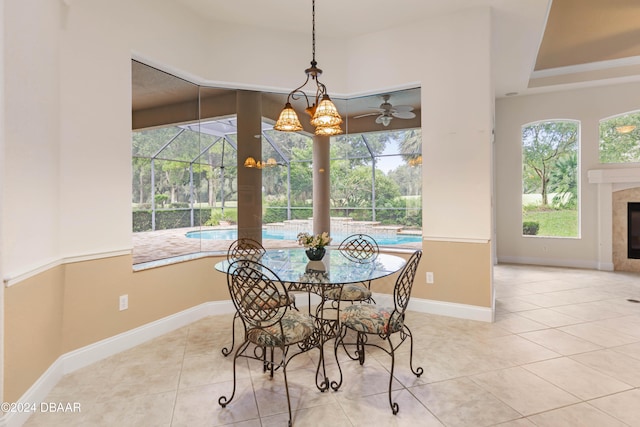 tiled dining area with a wealth of natural light, a tile fireplace, and ceiling fan