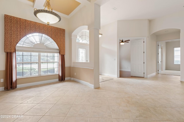 tiled empty room with crown molding, a healthy amount of sunlight, and ceiling fan