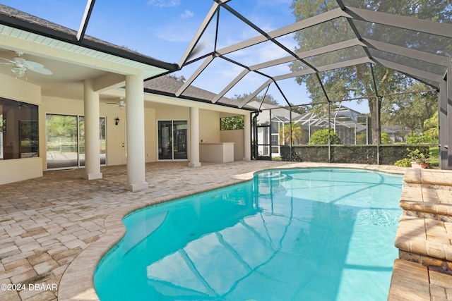 view of swimming pool with glass enclosure, a patio area, and ceiling fan