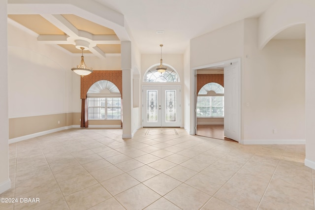 tiled foyer entrance featuring coffered ceiling, a wealth of natural light, french doors, and beam ceiling