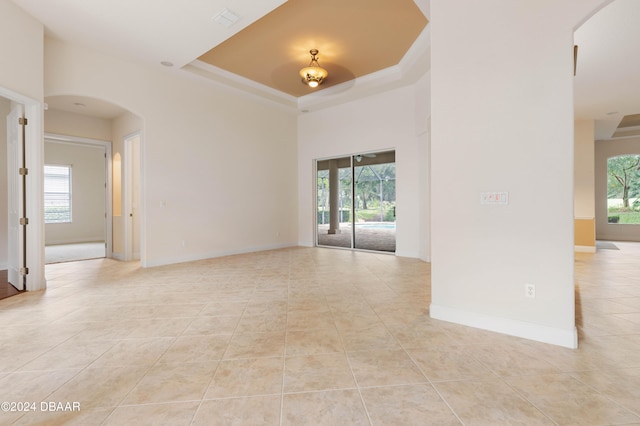 unfurnished room with plenty of natural light, light tile patterned floors, and a tray ceiling