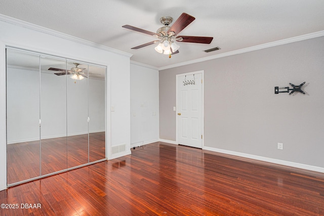 unfurnished bedroom featuring baseboards, crown molding, visible vents, and wood finished floors