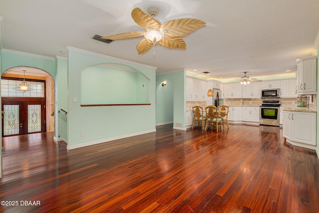 unfurnished living room featuring dark wood-style floors, ceiling fan, baseboards, and ornamental molding