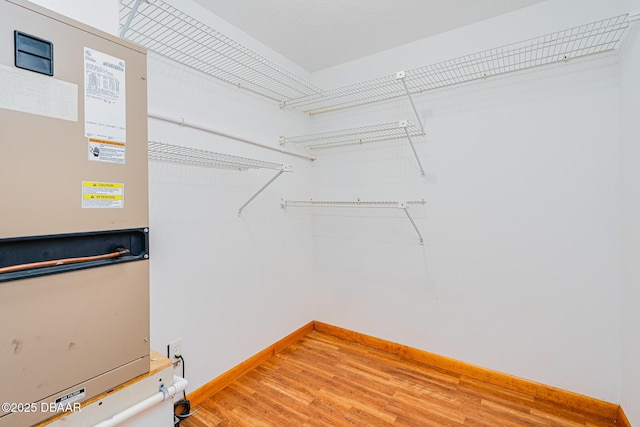 spacious closet with light wood-type flooring and heating unit