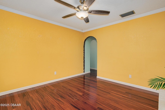 empty room featuring baseboards, visible vents, arched walkways, ornamental molding, and wood finished floors