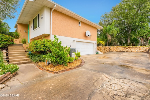 view of side of property with a garage, concrete driveway, and stairway