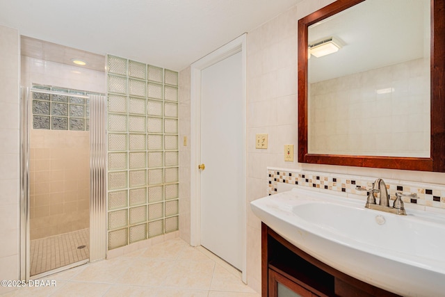 bathroom with tile walls, tasteful backsplash, a stall shower, vanity, and tile patterned floors