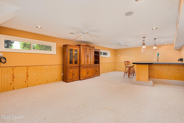 interior space with carpet floors, wainscoting, wooden walls, and a dry bar