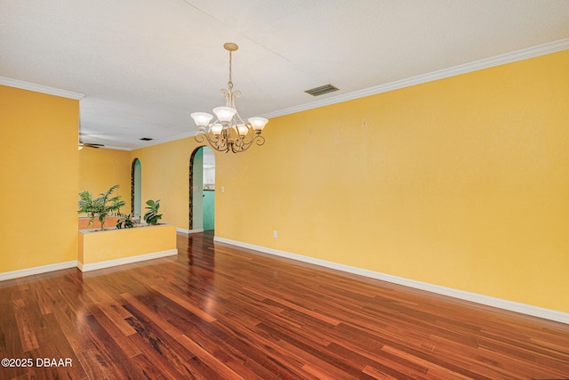 empty room with baseboards, ornamental molding, arched walkways, and wood finished floors