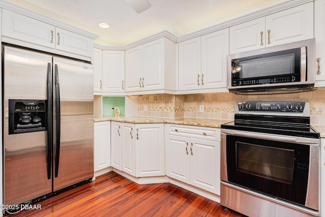 kitchen featuring stainless steel appliances, white cabinetry, dark wood finished floors, and tasteful backsplash