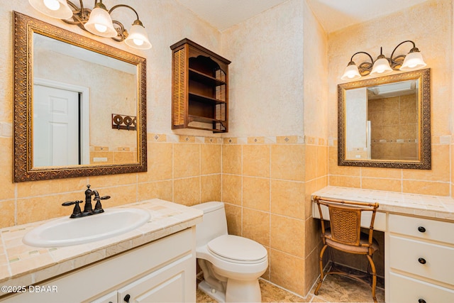 bathroom with toilet, a wainscoted wall, tile walls, and vanity