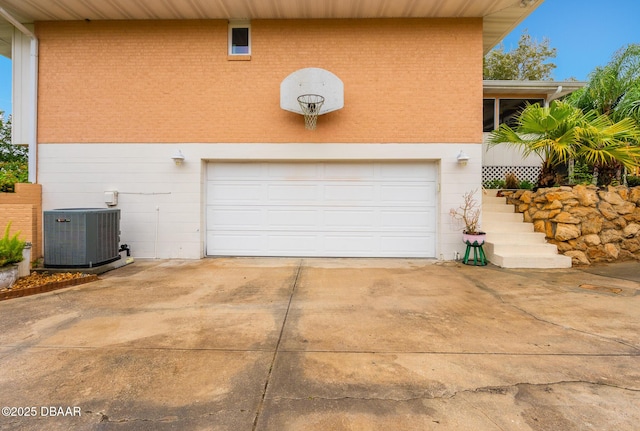 garage with central air condition unit and driveway