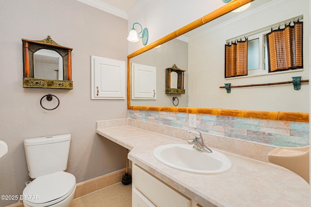 bathroom featuring baseboards, decorative backsplash, toilet, ornamental molding, and vanity