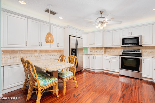 kitchen featuring dark wood-style flooring, tasteful backsplash, visible vents, appliances with stainless steel finishes, and white cabinets