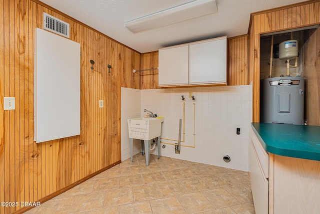 laundry area with wood walls, laundry area, visible vents, and electric water heater