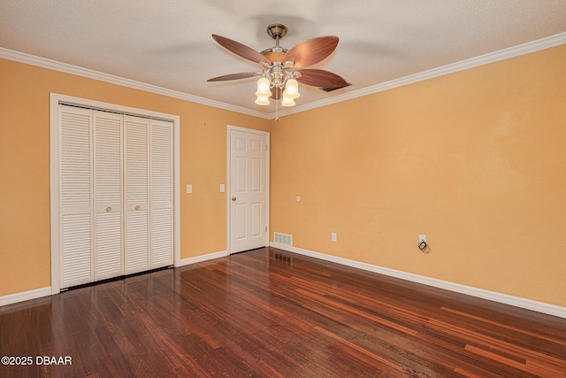 unfurnished bedroom featuring a closet, baseboards, wood finished floors, and ornamental molding