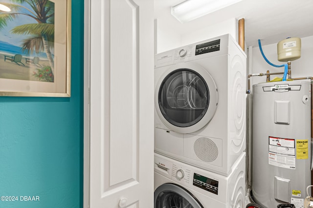 washroom with water heater and stacked washer and clothes dryer