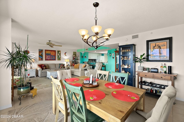 tiled dining area featuring a textured ceiling and ceiling fan with notable chandelier