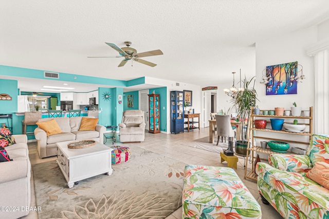 living room featuring light tile patterned flooring, ceiling fan with notable chandelier, and a textured ceiling