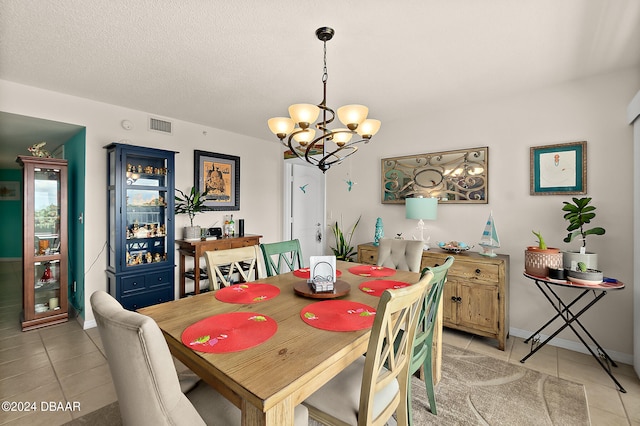 tiled dining space with a textured ceiling and an inviting chandelier