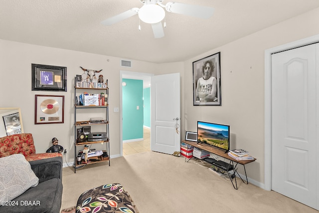 carpeted living room featuring ceiling fan and a textured ceiling