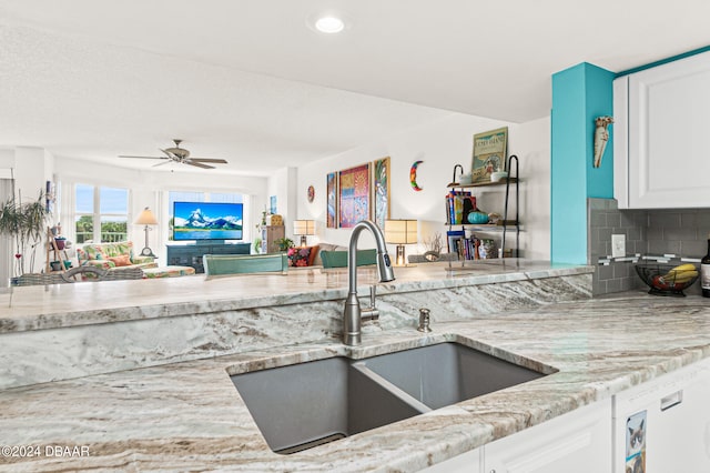 kitchen with decorative backsplash, sink, ceiling fan, light stone countertops, and white cabinetry