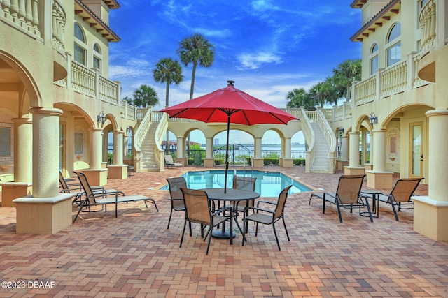 view of patio with a community pool and a balcony