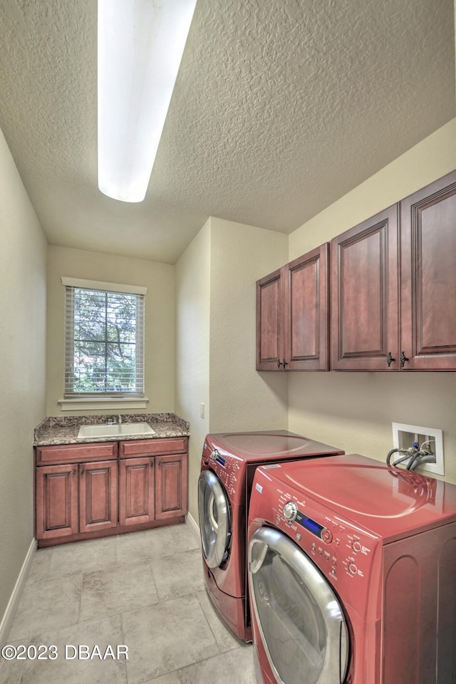 clothes washing area featuring sink, cabinets, a textured ceiling, and washer and dryer