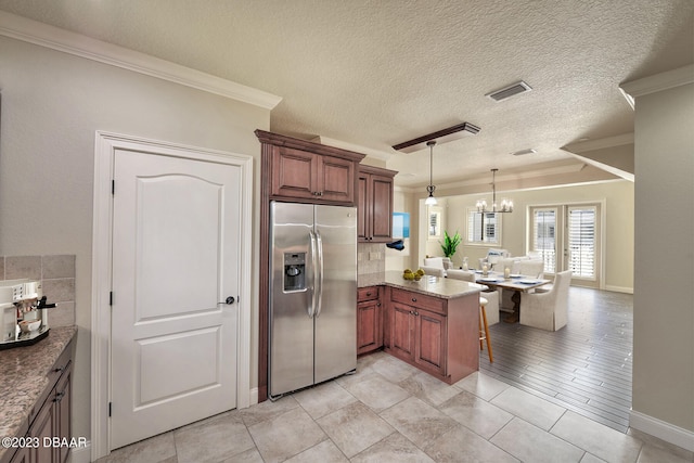 kitchen with ornamental molding, stainless steel refrigerator with ice dispenser, kitchen peninsula, and decorative light fixtures